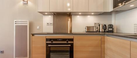 A modern kitchen with wooden cabinets, a built-in oven, a microwave, and a coffee maker.