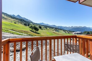 Enjoy a serene mountain view from this balcony with a table and chair for dining or relaxation.