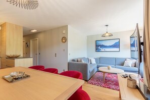 Relax in this stylish living area with a dining table, comfortable sofa, and a large television.