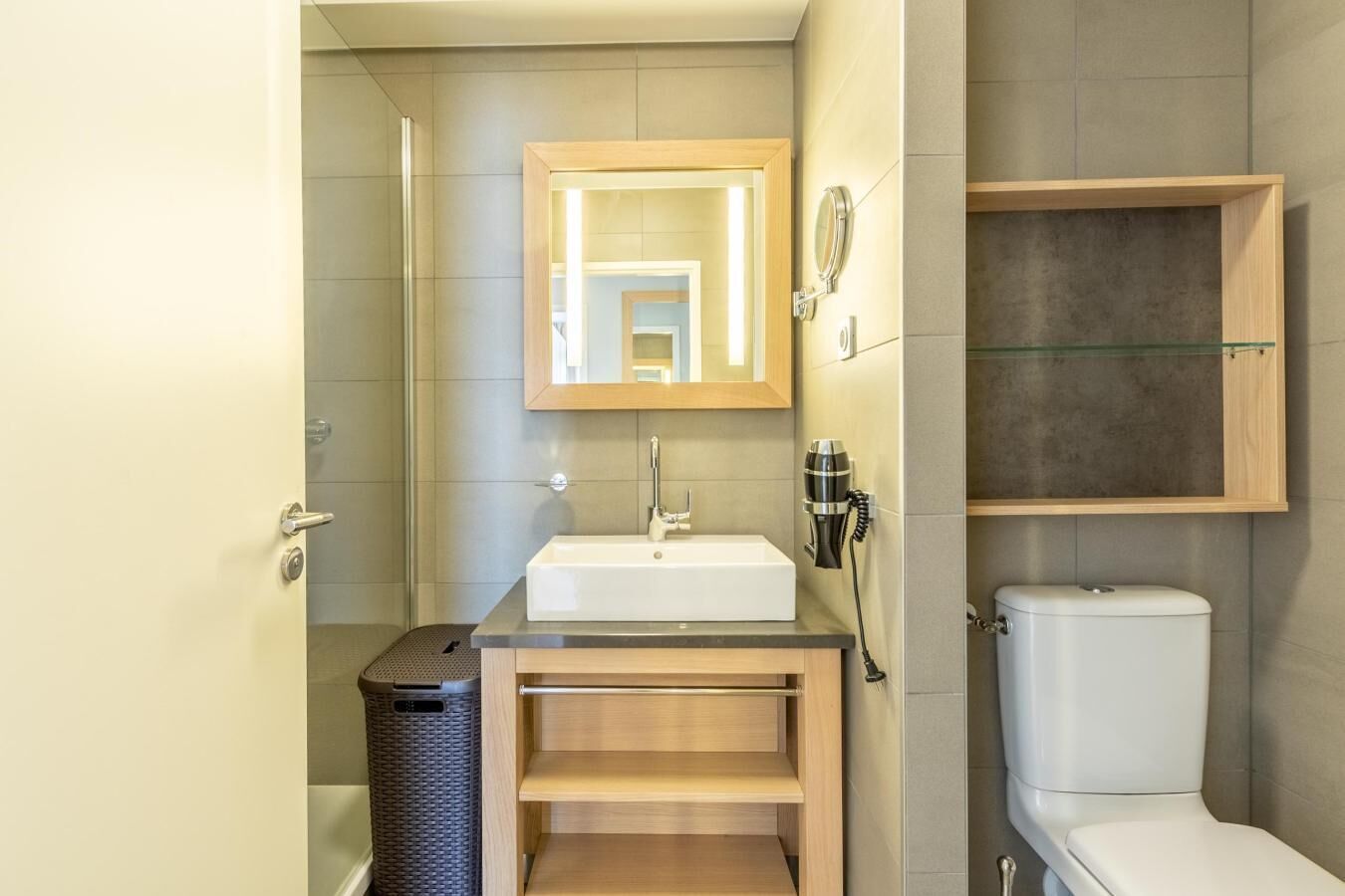 A compact bathroom with a sink, mirror, and toilet.
