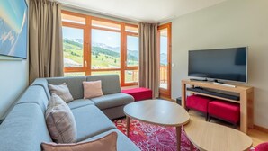 A modern living room with a sofa, a coffee table, and a flat-screen TV. - Ski-in/ski-out & foot of the slopes, 7th floor, view ski slopes, fitness, swimming pool, sauna (Bourg-Saint-Maurice)