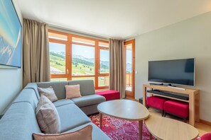 A modern living room with a sofa, a coffee table, and a flat-screen TV.