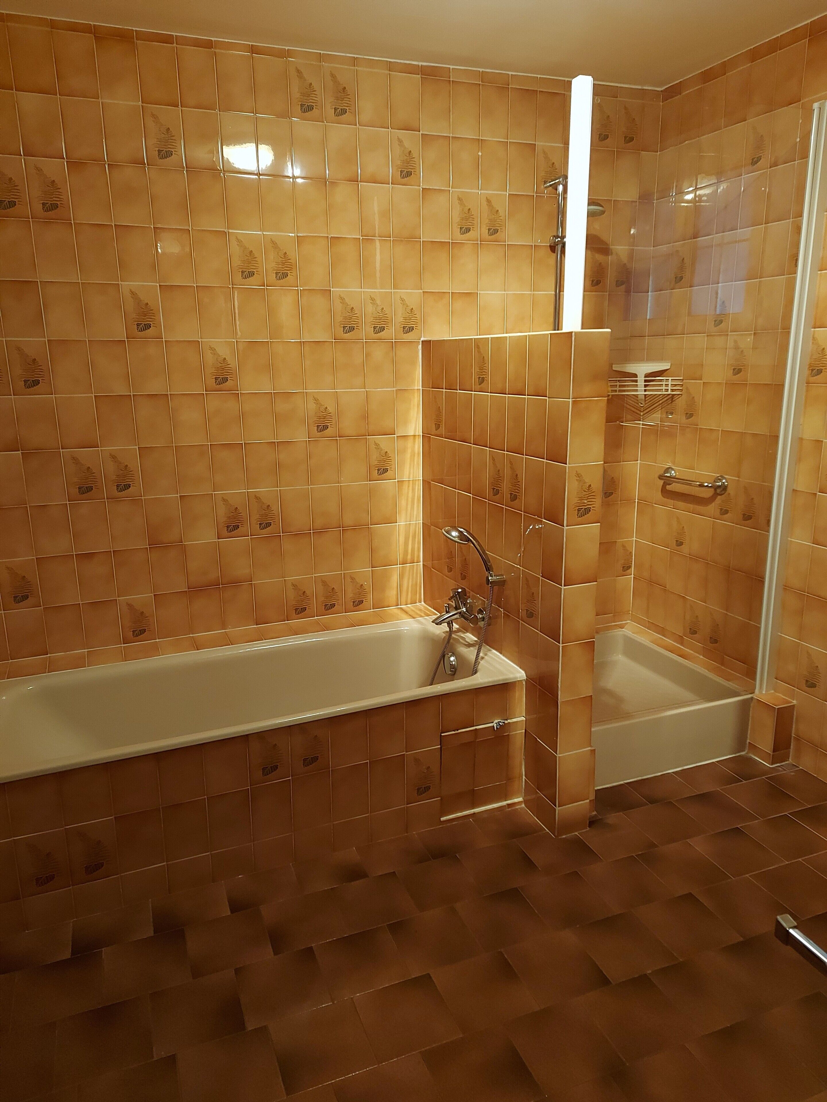 Une salle de bain avec une baignoire, une douche et un carrelage au sol.