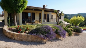 Una casa con porche cubierto, jardín de piedra y vistas a las colinas.