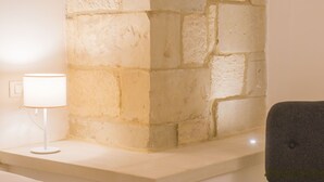 Esquina de pared de piedra con una lámpara blanca y una silla oscura.