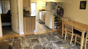 Una cocina compacta con una isla central, armarios de madera, un refrigerador y una zona de comedor con un banco.