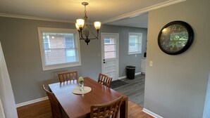 A dining area with a wooden table and chairs, a chandelier, and a clock on the wall. - Spacious, pet friendly, 2BR APT - 10min from OSU Campus (Worthington)