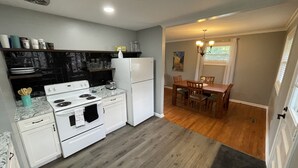 A kitchen with white appliances, a dining area with wooden chairs, and a rug leading to a door. - Spacious, pet friendly, 2BR APT - 10min from OSU Campus (Worthington)