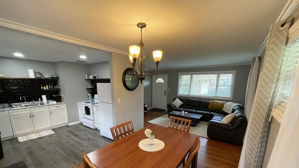 A modern kitchen with white cabinets, a dining table with chairs, a black sofa, and a large window. - Spacious, pet friendly, 2BR APT - 10min from OSU Campus (Worthington)
