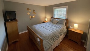 A bedroom with a bed, wooden headboard, bedside tables with lamps, a dresser, a television on a stand, and a window with blinds. - Spacious, pet friendly, 2BR APT - 10min from OSU Campus (Worthington)