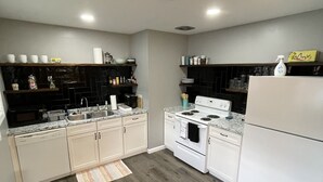 A modern kitchen with white cabinets, a black backsplash, and a white refrigerator. - Spacious, pet friendly, 2BR APT - 10min from OSU Campus (Worthington)