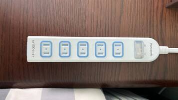 Una regleta blanca con cinco puertos USB y una pantalla, fijada a una superficie de madera.