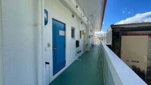 A corridor with a blue door marked 201, a window, and a door with a sign. - NAGO Sakura Resort Inn (Nago)