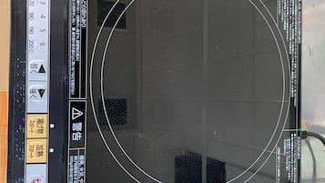 A black induction cooktop with a control panel and a circular cooking surface.