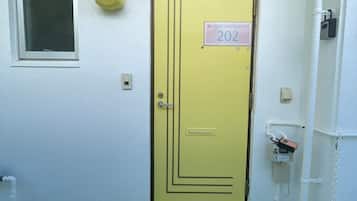 A yellow door with a sign reading "202" and a small window above it.