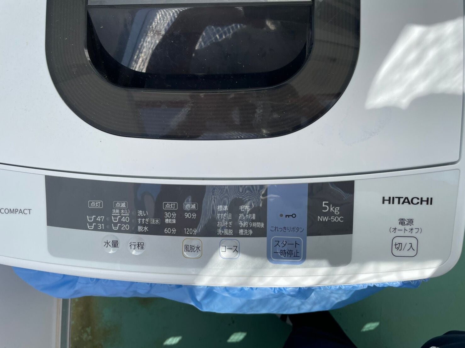 A car's control panel with various buttons and indicators, including a 5kg capacity label and the brand name HITACHI.