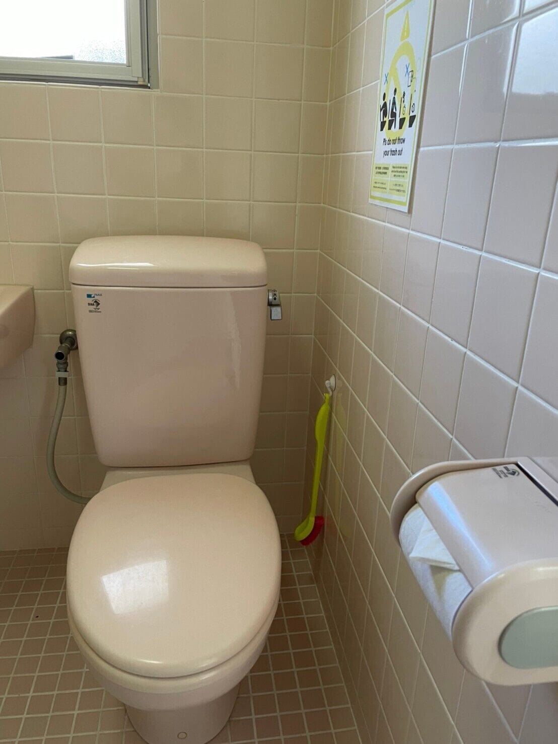 A toilet with a bidet attachment, a toilet paper holder, and a hand dryer.