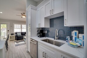 A modern kitchen with white cabinets, a blue-tiled backsplash, and a stainless steel sink. - Blue Lagoon (Anna Maria)