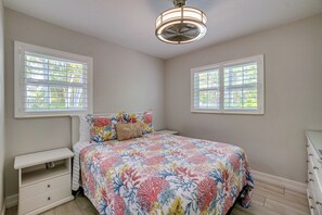 A bedroom with a bed, two windows, a nightstand, and a dresser. - Blue Lagoon (Anna Maria)