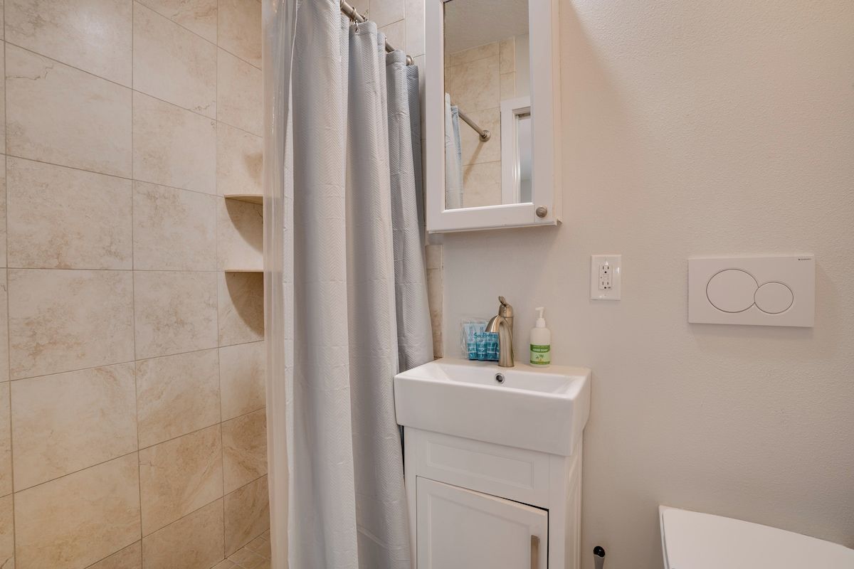 A bathroom with a shower, a sink, and a mirror.