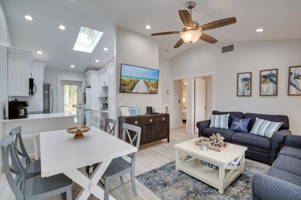 A spacious living area with a ceiling fan, a dining table with chairs, a sofa, and a coffee table.