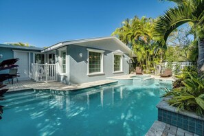 A house with a swimming pool, surrounded by palm trees and a white fence. - Anchor Splash (Anna Maria)