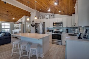 A modern kitchen with white cabinetry, stainless steel appliances, and a wooden ceiling. - Anchor Splash (Anna Maria)