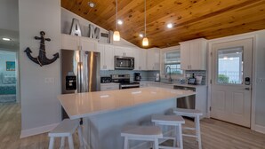 Una cocina moderna con gabinetes blancos, electrodomésticos de acero inoxidable y techo de madera.