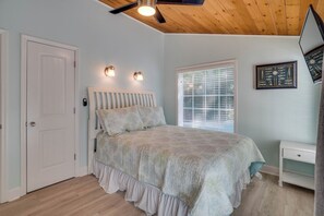 A bedroom with a bed, a ceiling fan, a window with blinds, and a door. - Anchor Splash (Anna Maria)