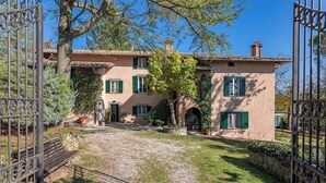 A two-story building with a gravel driveway, green shutters, and a stone archway.