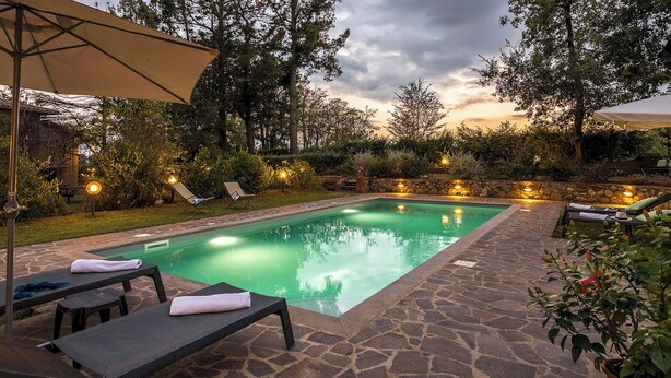 A swimming pool with lounge chairs and a stone patio.