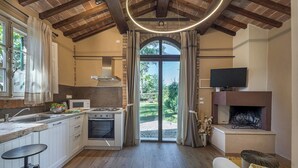 A modern kitchen with a built-in oven, a microwave, and a gas stove. There is a large window with curtains, a fireplace, and a television mounted above it.
