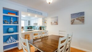 Un comedor con una mesa de madera y sillas blancas, una cocina al fondo y un letrero que dice "ANA MARIA ISLAND".