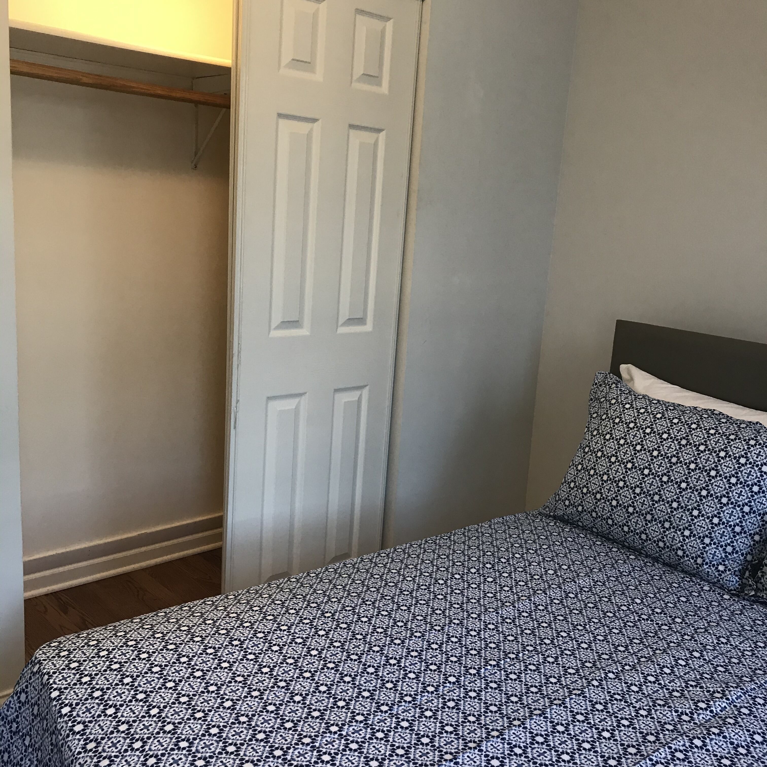 Une chambre à coucher avec un lit, une couvre-lit à motifs, une tête de lit et une porte blanche.