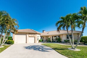 A two-story house with a driveway, palm trees, and a clear blue sky. - Tropical Waterfront Villa with Heated Pool & Spa (Punta Gorda)