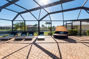 A covered outdoor area with lounge chairs and a round seating area with cushions. - Tropical Waterfront Villa with Heated Pool & Spa (Punta Gorda)