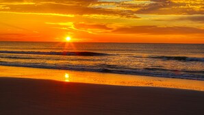Ein Sonnenuntergang über einem Strand mit Wellen.