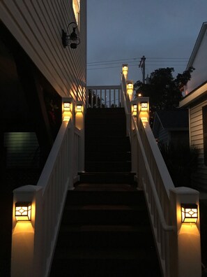 Staircase with handrails leads to a landing, flanked by exterior lighting fixtures.