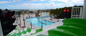 En vandpark med flere pools og vandrutsjebaner, omgivet af palmer og udsigt til havet.