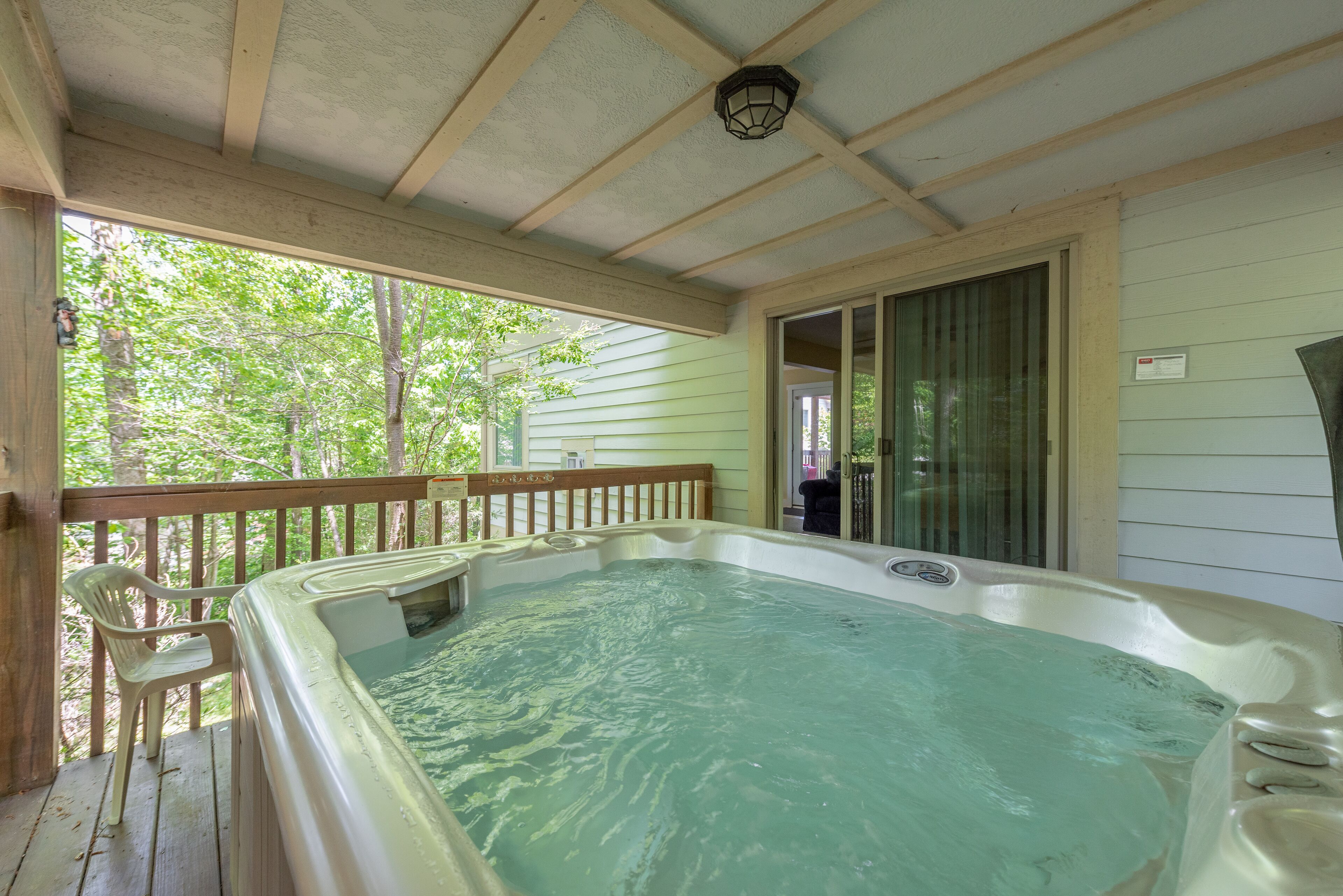 Un jacuzzi en una terraza de madera con vista a los árboles.