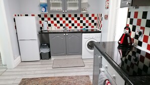 A compact kitchen with a washing machine, a refrigerator, and a sink.