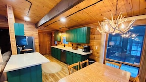 L’intérieur chaleureux d’un chalet comprend un coin repas, une cuisine et une grande fenêtre.