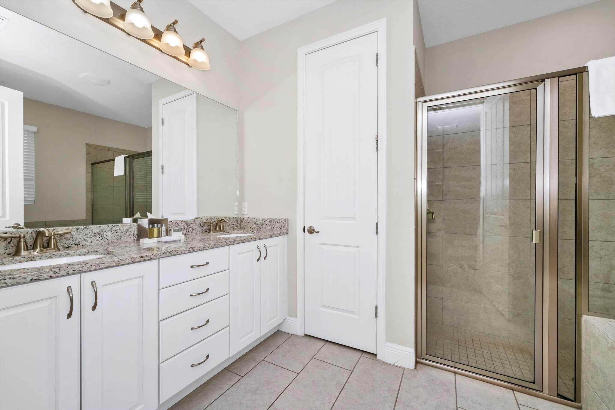 Une salle de bain avec un meuble-lavabo blanc, un grand miroir et une cabine de douche en verre.