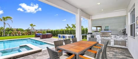 A backyard with a pool, outdoor dining area, and a barbecue grill.