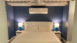 Ein Schlafzimmer mit einem Bett, zwei Nachttischen, zwei Wandlampen und einem Deckenventilator.