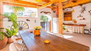 A wooden dining table with chairs, a yellow pendant light, and potted plants. - Cubo's Finca Las Cuatro Lunas (Alhaurin de la Torre)