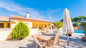 A patio with a wooden table and chairs, a white umbrella, and a swimming pool. - Cubo's Finca Las Cuatro Lunas (Alhaurin de la Torre)