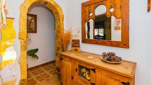 A room with a stone archway, wooden cabinet, and a mirror on the wall. - Cubo's Finca Las Cuatro Lunas (Alhaurin de la Torre)