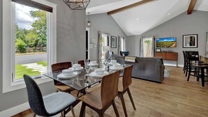 A dining area with a glass table set for six, wooden chairs, and a modern pendant light.