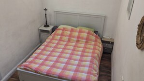 Een slaapkamer met een bed, nachtkastje, lamp en een kledingkast.